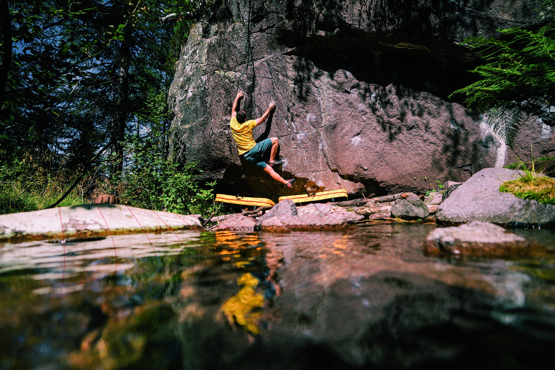 Climber on a boulder above water in Val di Sadole