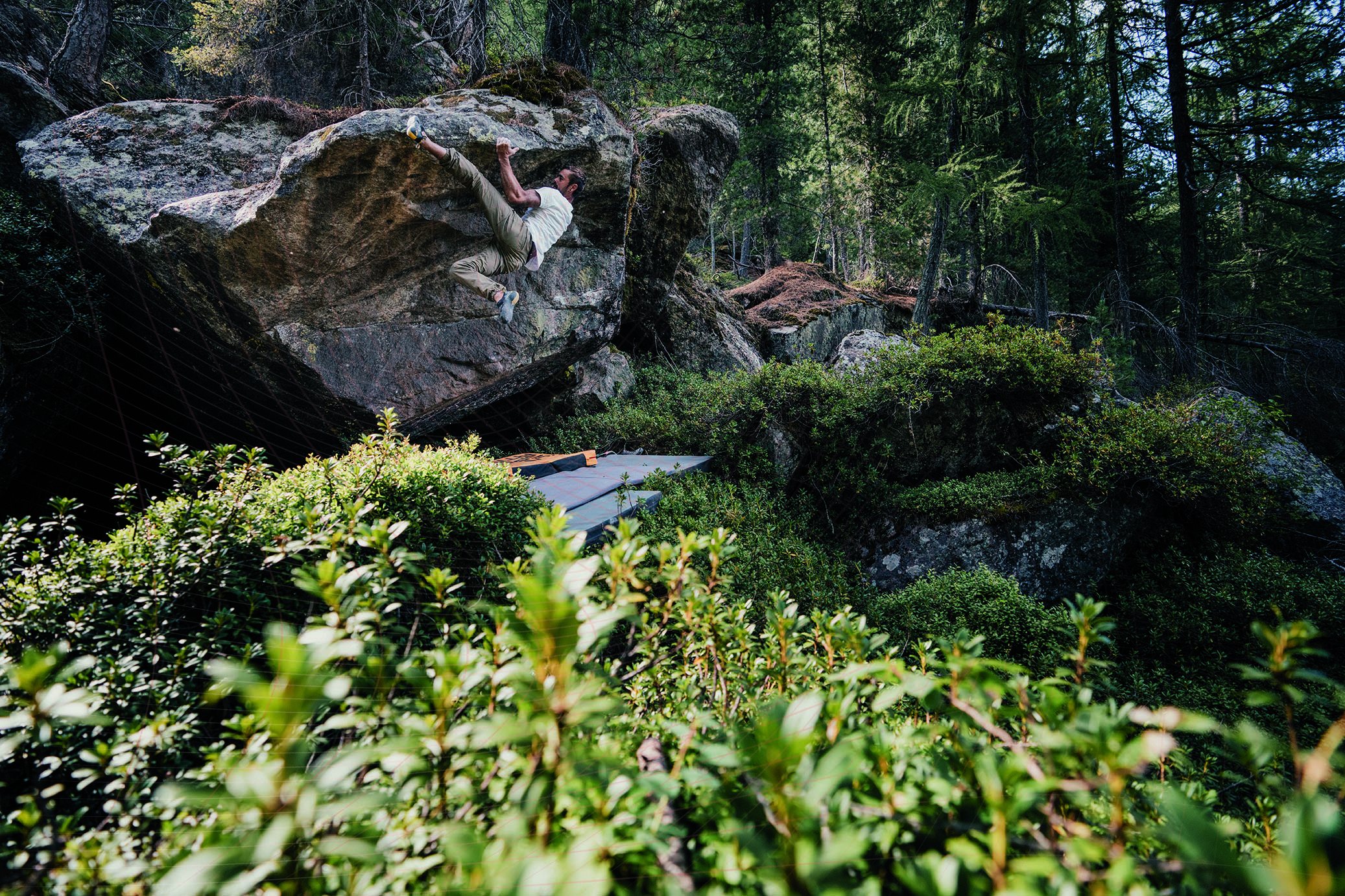 Climber heel hooking on a forest boulder in Val di Sadole